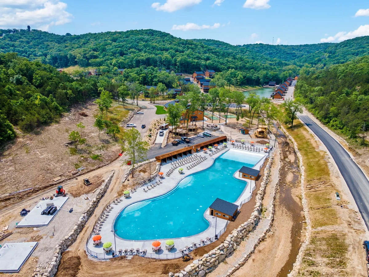 A large swimming pool surrounded by greenery, with poolside lounge chairs and wooden cabanas providing spaces for relaxation and socializing. The inviting pool area is ideal for cooling off after hiking or lake activities, and the overall mood is serene and recreational.