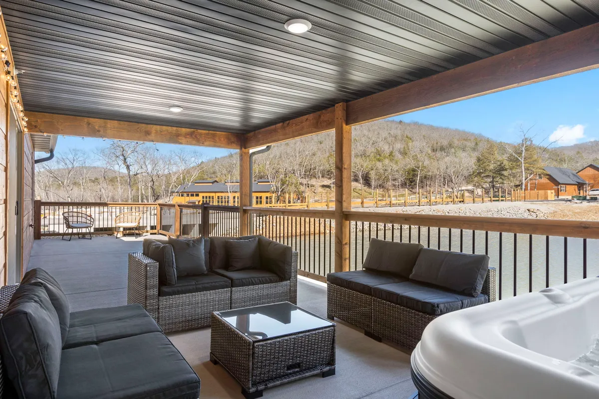 A welcoming outdoor seating area on a wooden deck, complete with a bubbling hot tub and picturesque views of water and distant mountains. The setup includes comfortable chairs for enjoying the scenery, and the mood suggests both morning tranquility and magical evenings under the stars.