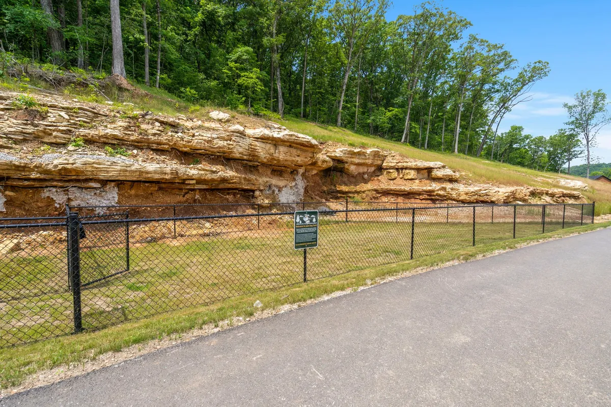A serene exterior shot featuring unique rock formations, a fenced area, and a signpost, all set in a peaceful natural landscape. The scene invites exploration, hiking, and enjoying the outdoors.