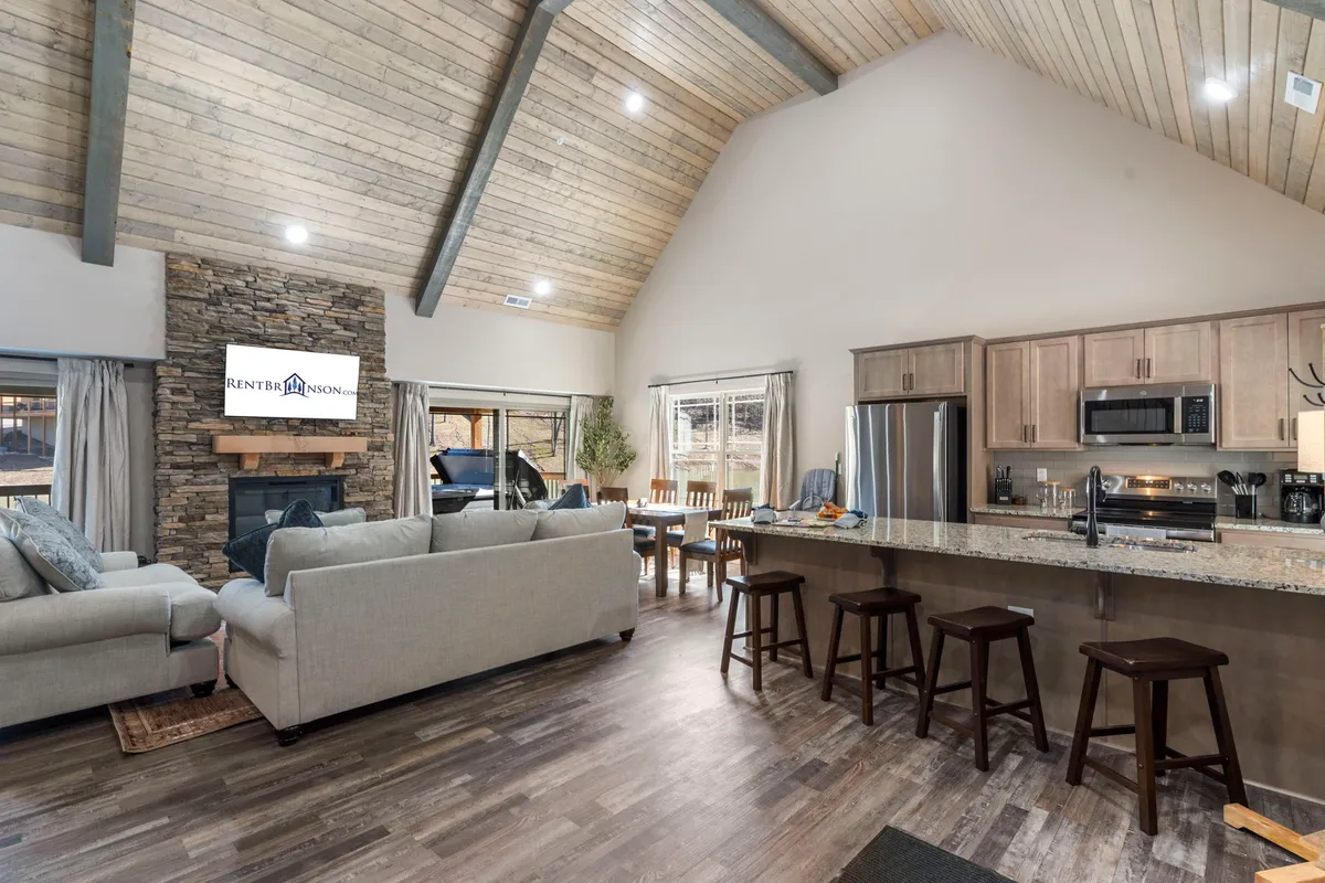 An inviting open-plan space with a stone fireplace, kitchen island, comfortable sofas, and a dining table. The image illustrates how the kitchen, living room, and dining area flow together for family gatherings and group activities.