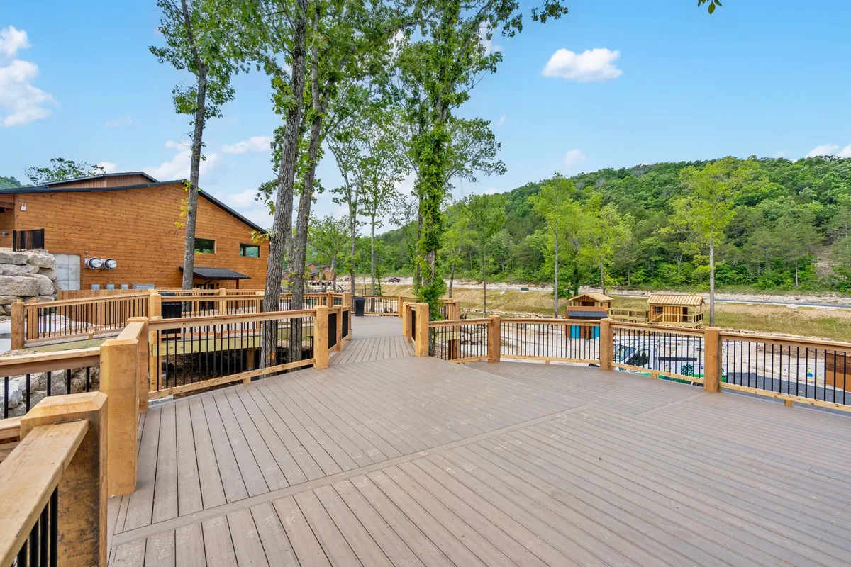 A tranquil deck area nestled among trees, with ample outdoor seating and scenic forest views. The arrangement is ideal for relaxing outdoors, sharing stories, or enjoying a meal surrounded by nature. The atmosphere feels welcoming and safe for families and pets alike.