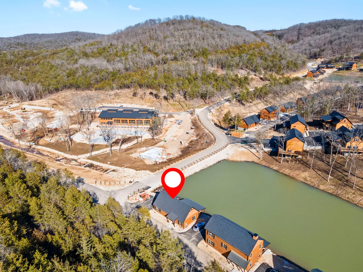 A serene lakeside scene featuring a cluster of cozy cabins nestled among lush greenery, with the calm lake reflecting the surrounding landscape. The setting is peaceful and inviting, perfect for quiet moments together by the water.